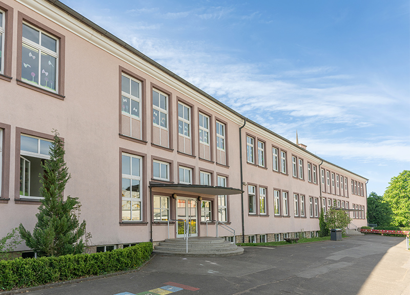 Schulhaus Lülsfelder Weg mit blauem Himmel und Sonnenschein