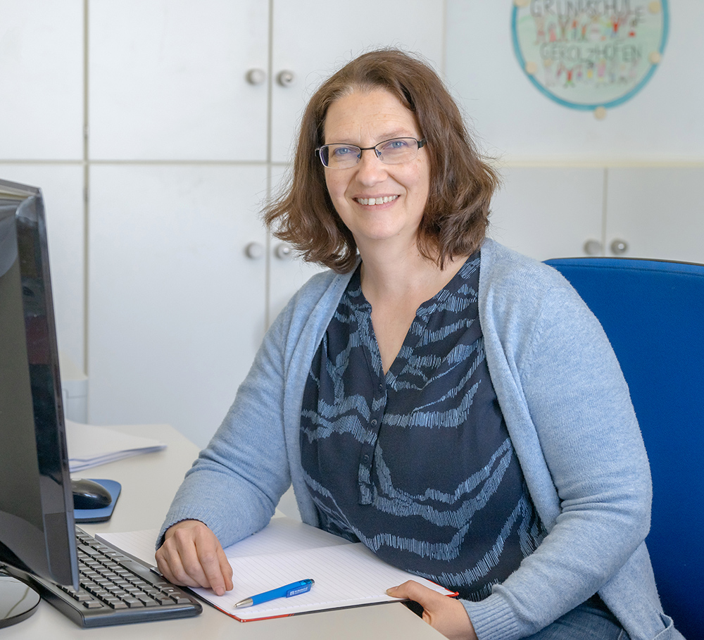 Sekretärin sitzt am Arbeitsplatz und schaut in die Kamera