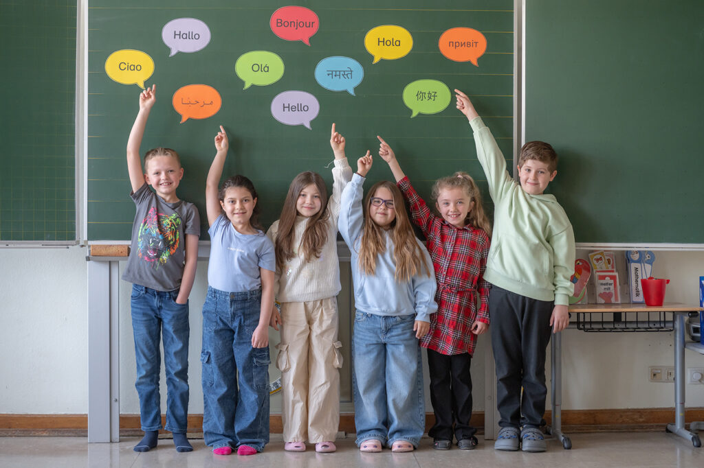 Kinder deutsch auf Sprechblasen an der Tafel mit Hallo in unterschiedlichen Sprachen