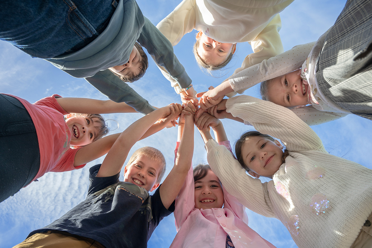 Kinder halten sich an den Händen und schauen von oben in die Kamera