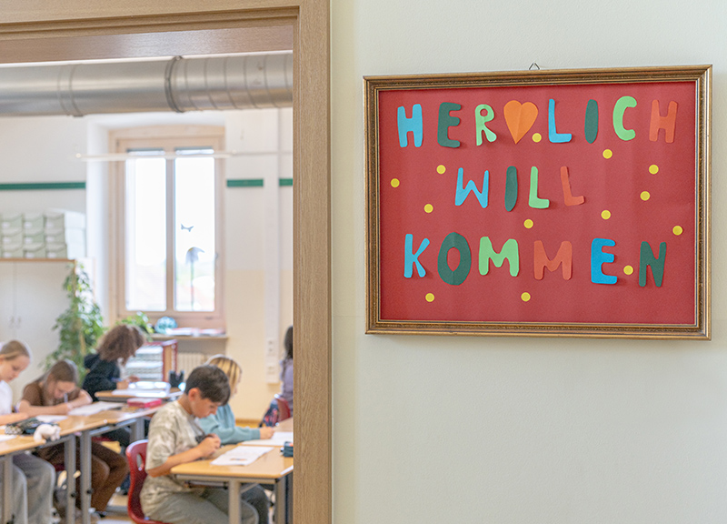 Offenes Klassenzimmer mit Schild Herzlich Willkommen